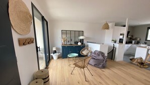 A modern living room with a wooden floor, a blue cabinet, a round table, a wicker chair, and a bean bag. - HOUSE LE CLOS JOLY NEAR TRAIN STATION 3 BEDROOMS (Les Sables-d'Olonne)
