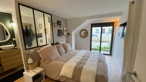 A bedroom with a large bed, a bedside table with a lamp, a mirror, and a window with a view of the outside. - HOUSE LE CLOS JOLY NEAR TRAIN STATION 3 BEDROOMS (Les Sables-d'Olonne)