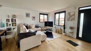 A modern living room with a sofa, TV, and a dining area with chairs and a table. - HOUSE LE CLOS JOLY NEAR TRAIN STATION 3 BEDROOMS (Les Sables-d'Olonne)