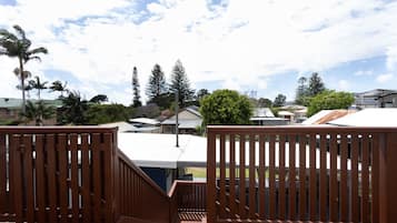 Une terrasse en bois offrant une vue sur des maisons et des arbres en arrière-plan.
