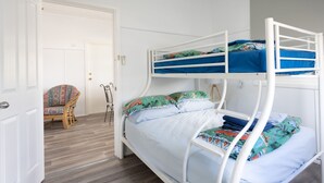 Camera con letto a castello, una porta, una sedia e una lampada.