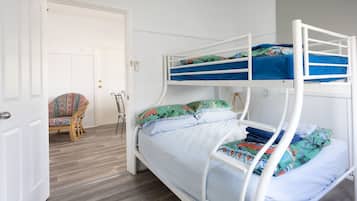 A bunk bed room with a door, a chair, and a lamp.