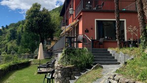 A red building with a balcony, stone steps, and outdoor seating. - Villa Angelina (Cannero Riviera)