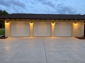 A garage with three white doors, each with a light fixture above. - Comfortable, Peaceful Stay Near Tampa & Plant City (Seffner)