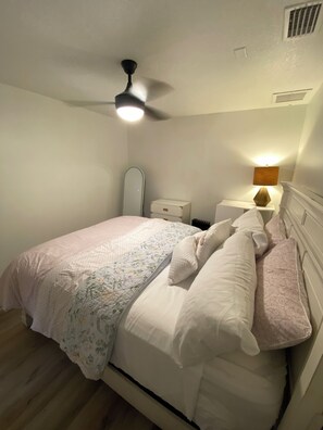 A bedroom with a bed, a bedside table, a lamp, a ceiling fan, and a mirror. - Comfortable, Peaceful Stay Near Tampa & Plant City (Seffner)