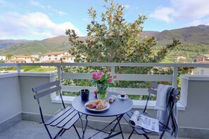 A balcony with a table set for breakfast, including croissants, coffee, and a vase of flowers. - MatesHouse-La Cappelluccia byHomeAndMore (San Potito Sannitico)