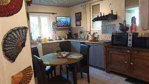 A compact kitchen with a dining area, featuring a TV, a microwave, and a sink. - Natural setting and source of art, river, animals welcome, magical calm! (Saulx-lès-Champlon)