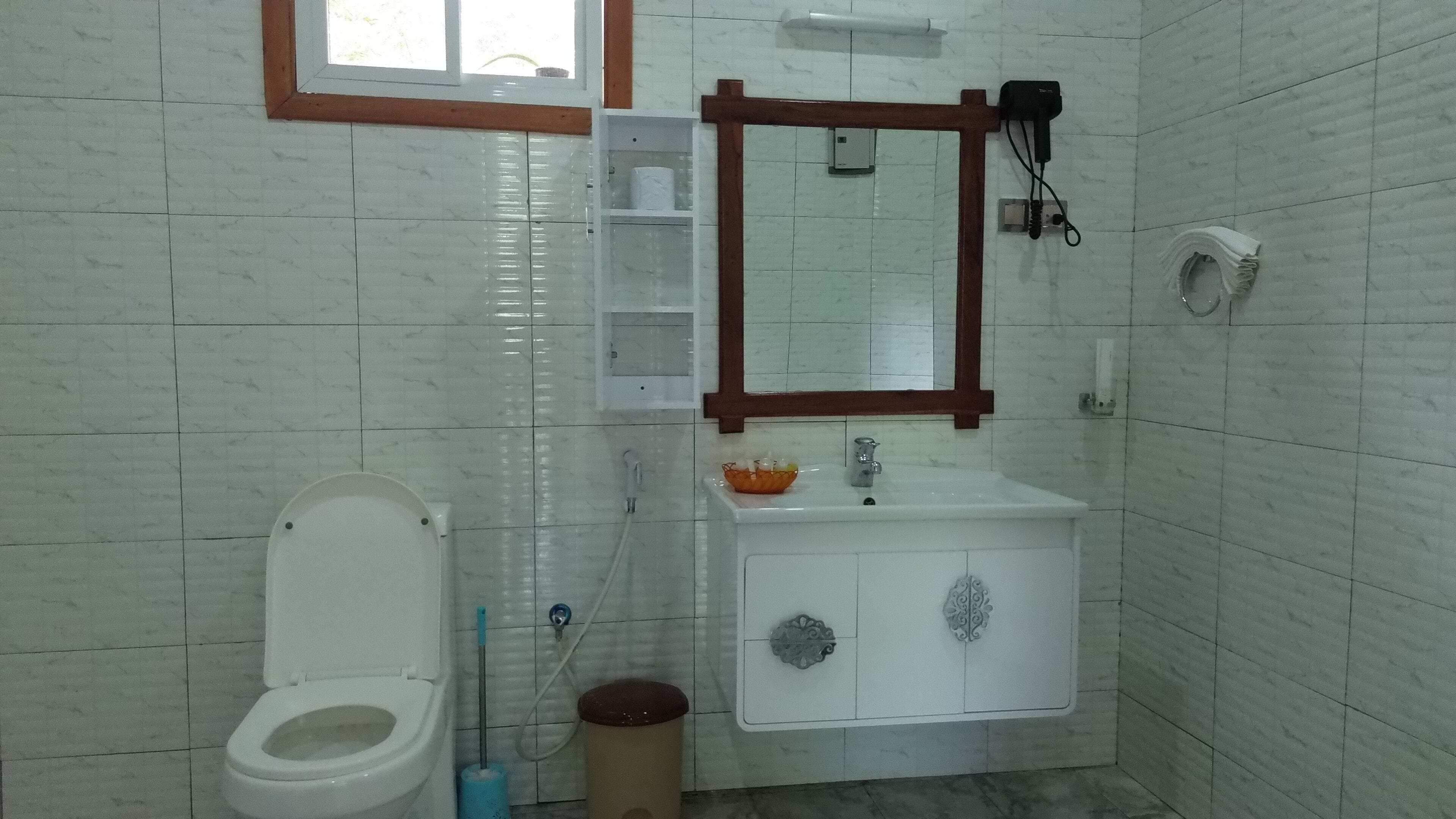 A bathroom with a toilet, sink, and mirror.