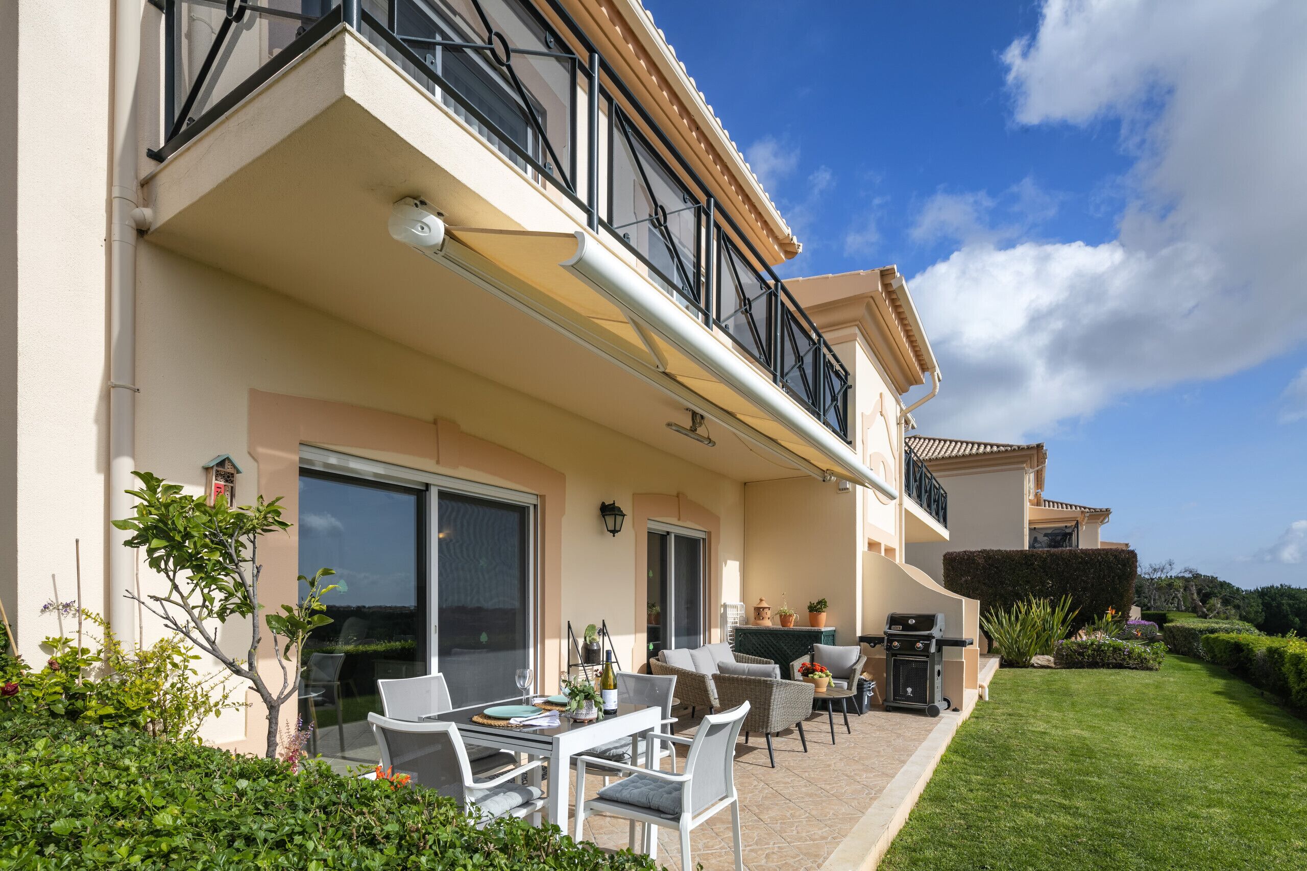 A two-story house with a balcony, outdoor seating, and a well-maintained lawn.