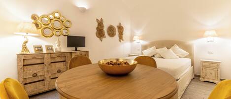 Un dormitorio acogedor con una cama, mesitas de noche y una mesa redonda con sillas.
