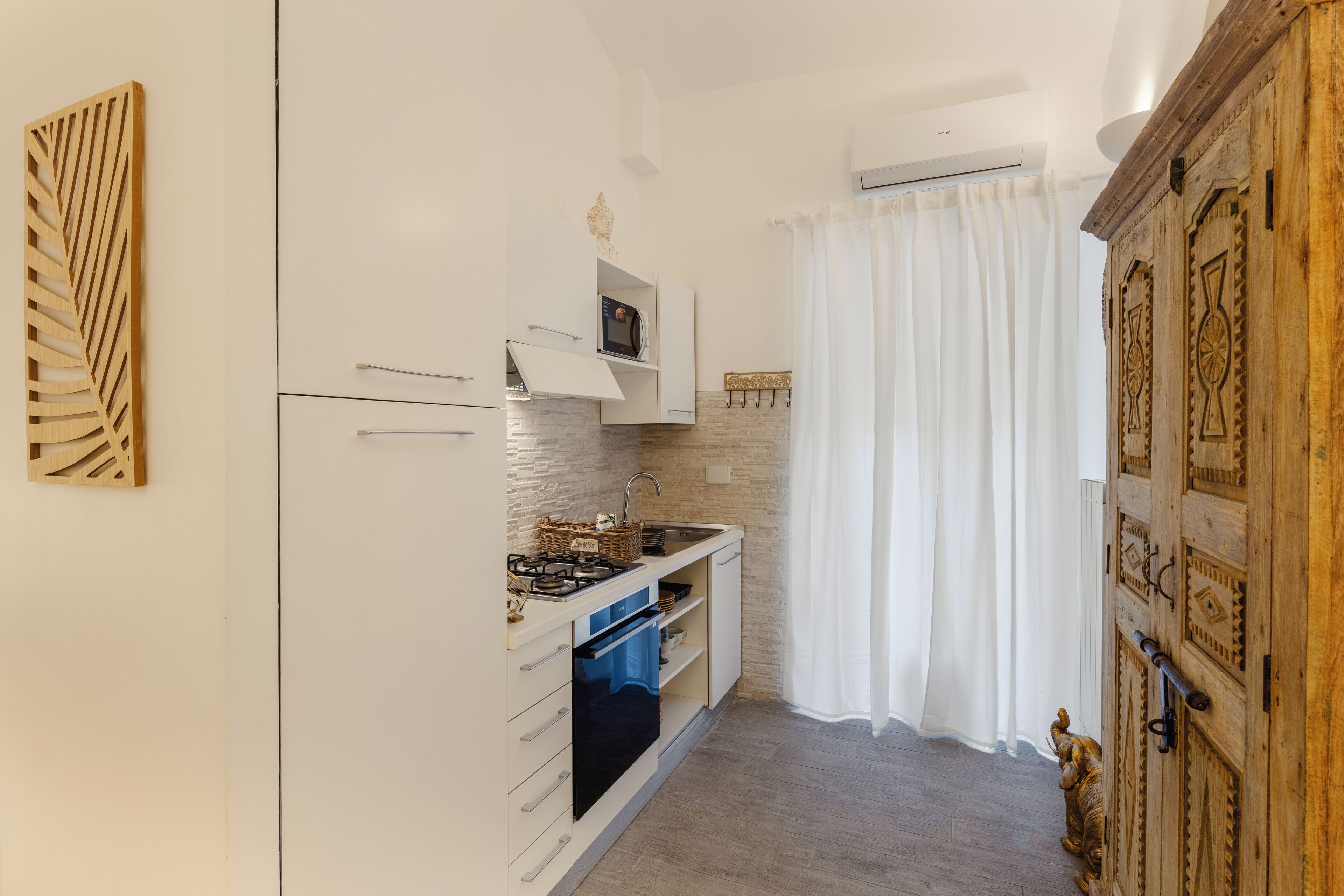A compact kitchen with white cabinetry, a built-in microwave, and a gas stove.