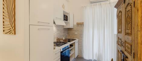 A compact kitchen with white cabinetry, a built-in microwave, and a gas stove.