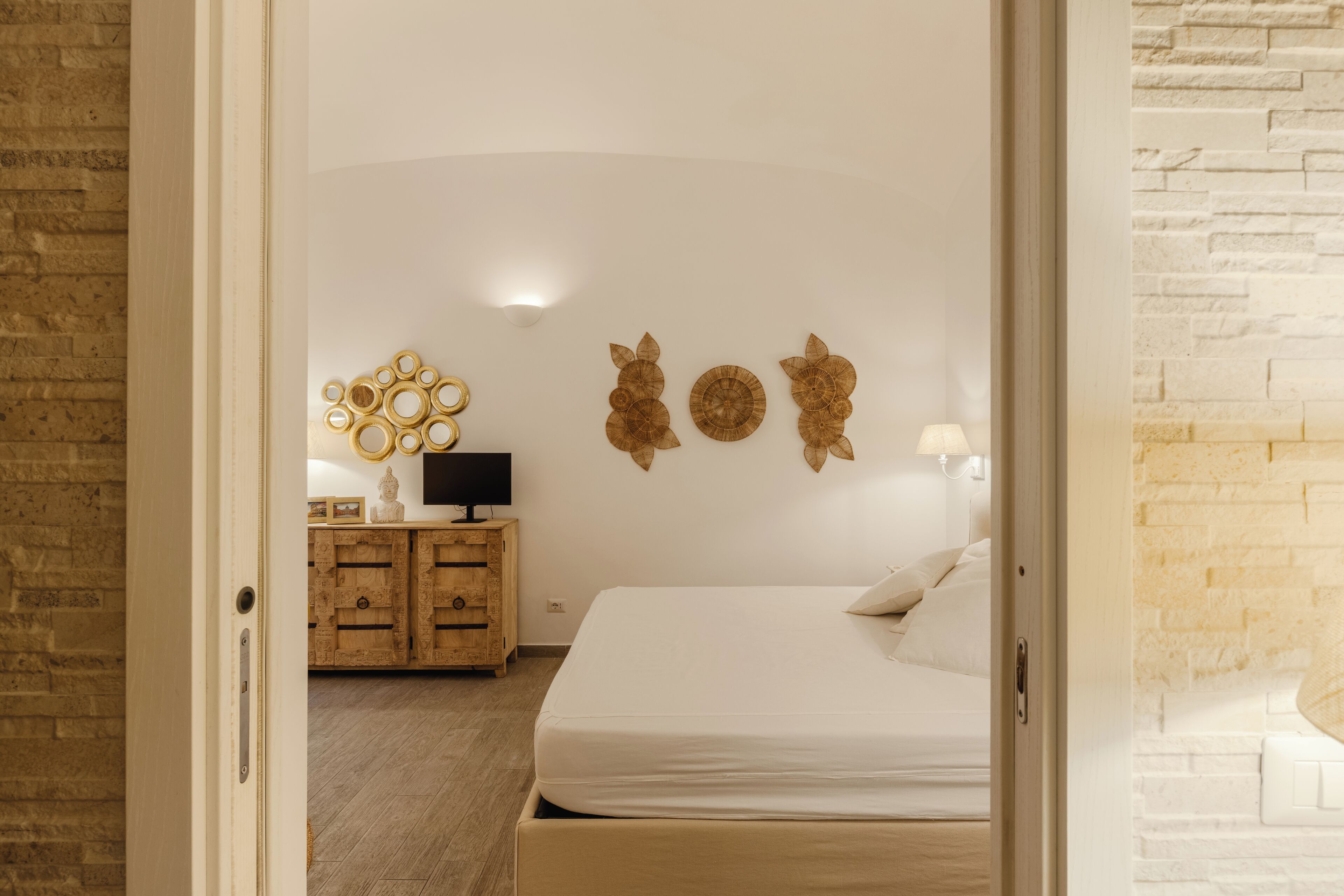 A bedroom with a bed, a wooden dresser, and wall decor.