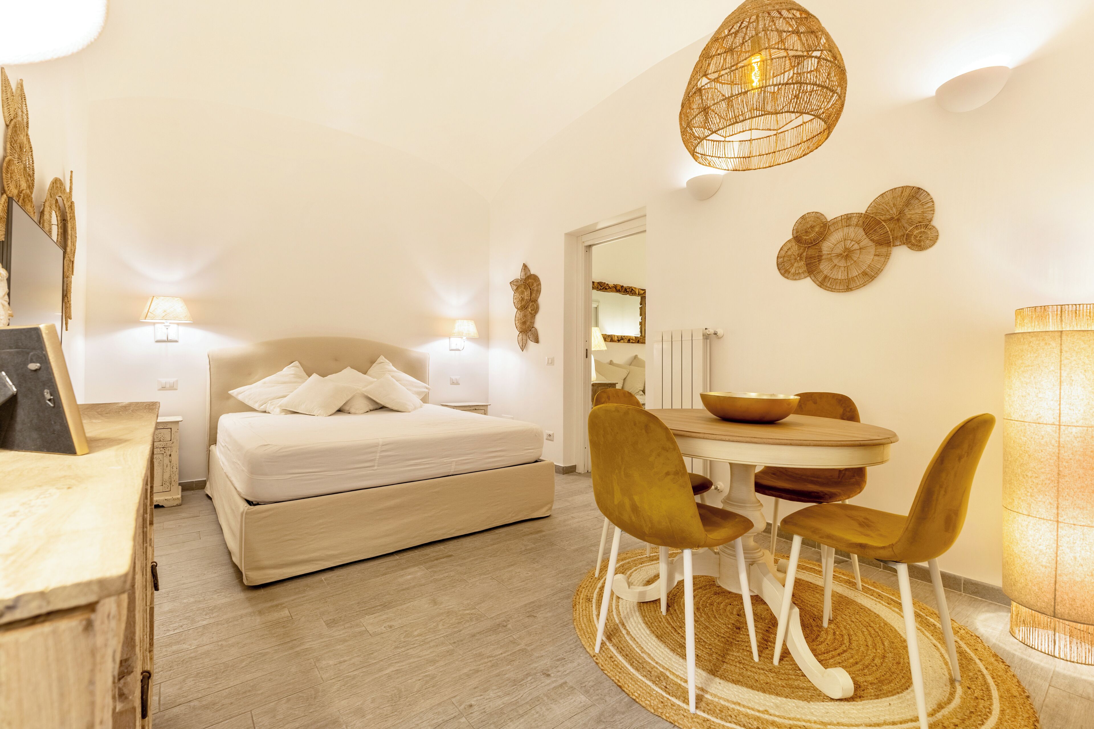 Une chambre moderne comprenant un lit, des tables de chevet, un coin repas avec des chaises et un lustre.