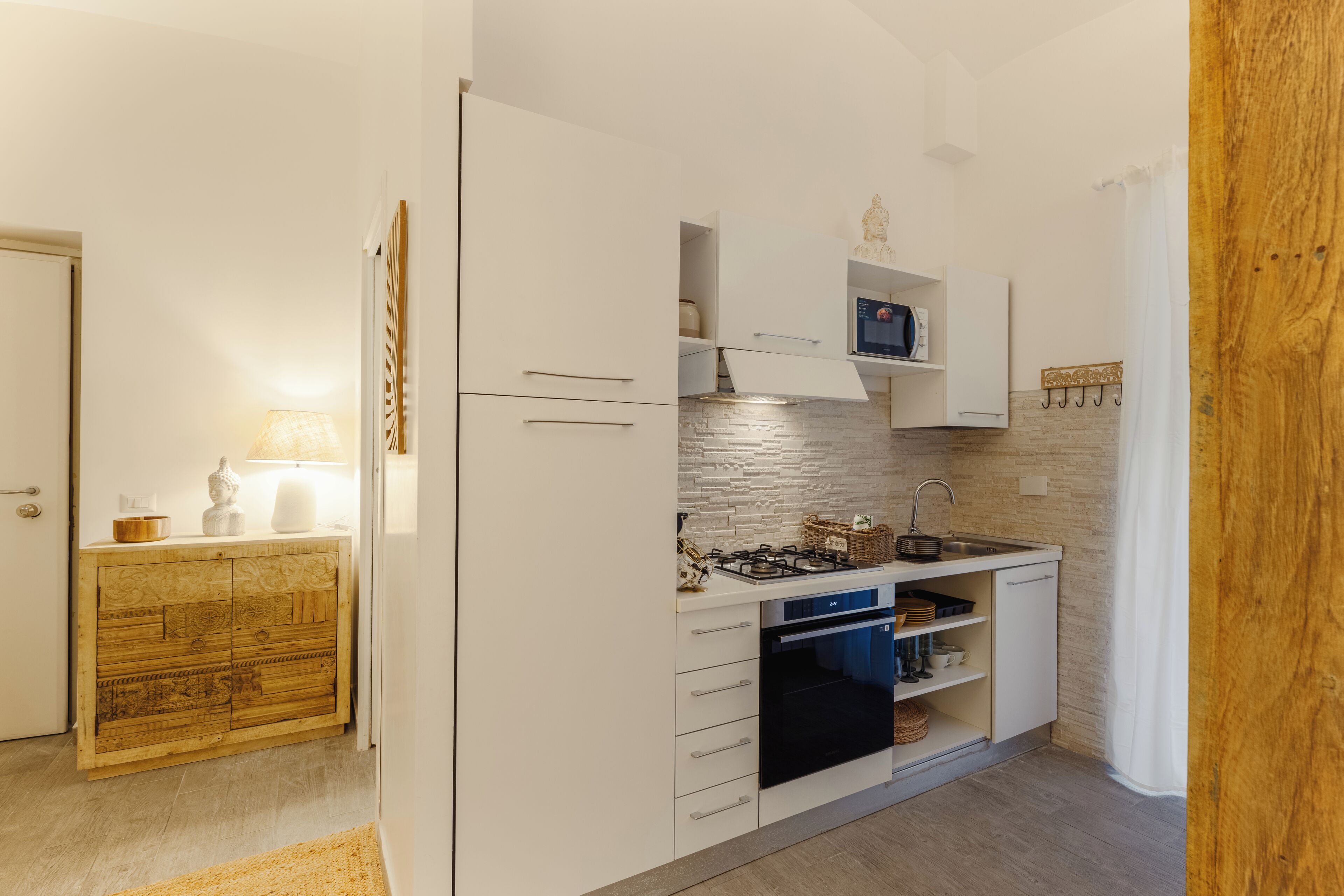 A compact kitchen with white cabinetry, a built-in oven, and a gas stove.
