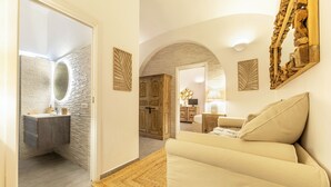 Ein modernes Interieur mit einer Steinwand, Holzschränken, einem beigen Sofa und einem runden Spiegel.