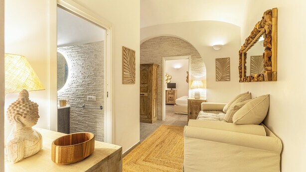 Ein modernes Interieur mit einer Steinwand, einer Holzskulptur, einem beigen Sofa und einem Spiegel.