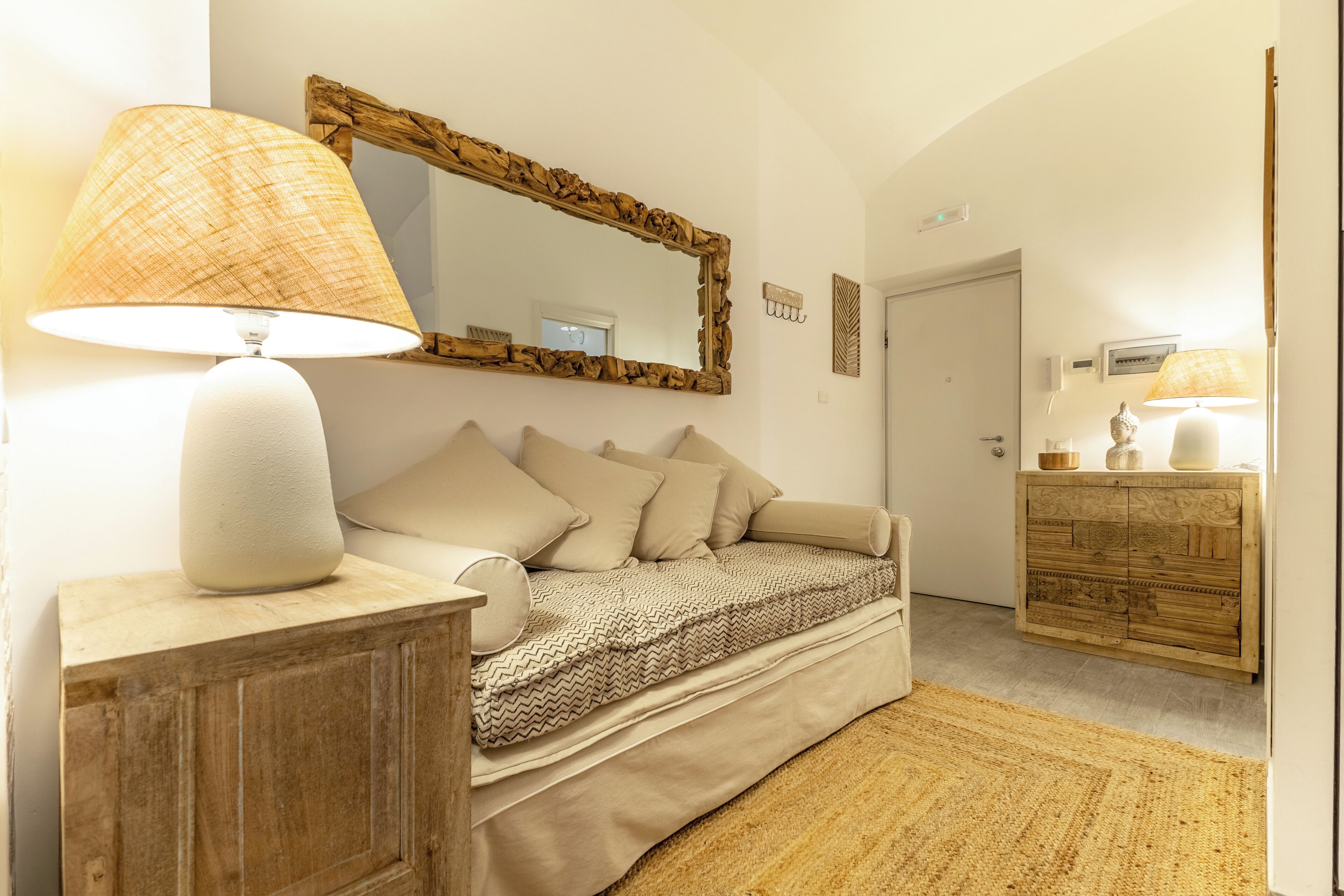 A bedroom with a bed, a wooden cabinet, a mirror, and a lamp.