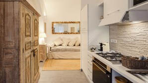 Ein kleines Schlafzimmer mit einem Holzschrank, einem Bett mit weißer Bettwäsche, einer Nachttischlampe und einem Spiegel an der Wand.
