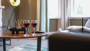 Ein Zimmer mit einem runden Tisch, zwei Weingläsern, einem Kerzenhalter und einem Sofa.