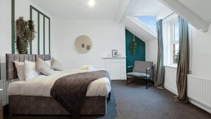 Ein Schlafzimmer mit einem Bett, einem Sessel, einer runden Wanddekoration und einem Fenster mit Vorhängen.