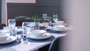 Ein Esstisch, gedeckt mit Tellern, Schüsseln, Gläsern und Besteck.