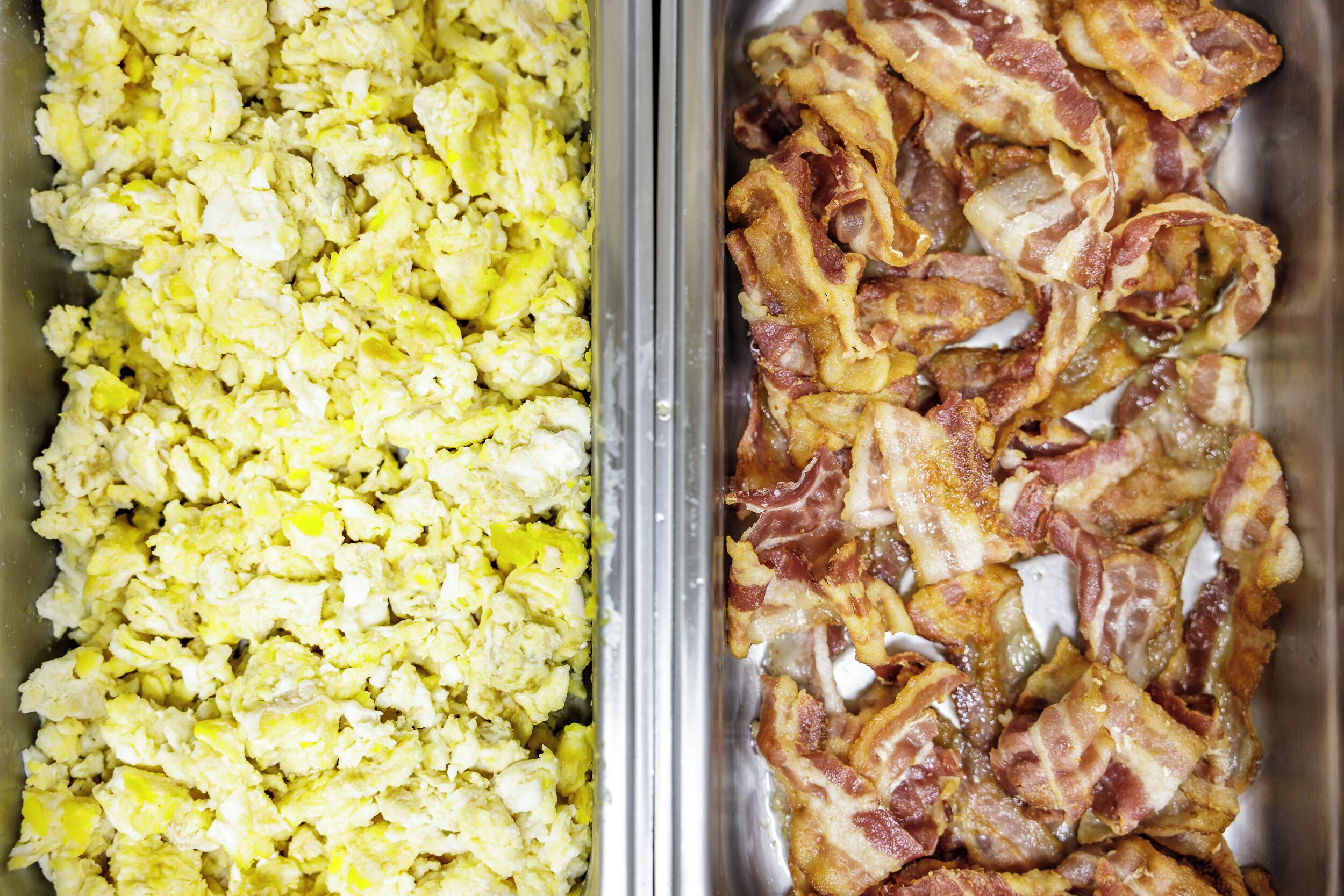 A buffet with scrambled eggs and bacon.