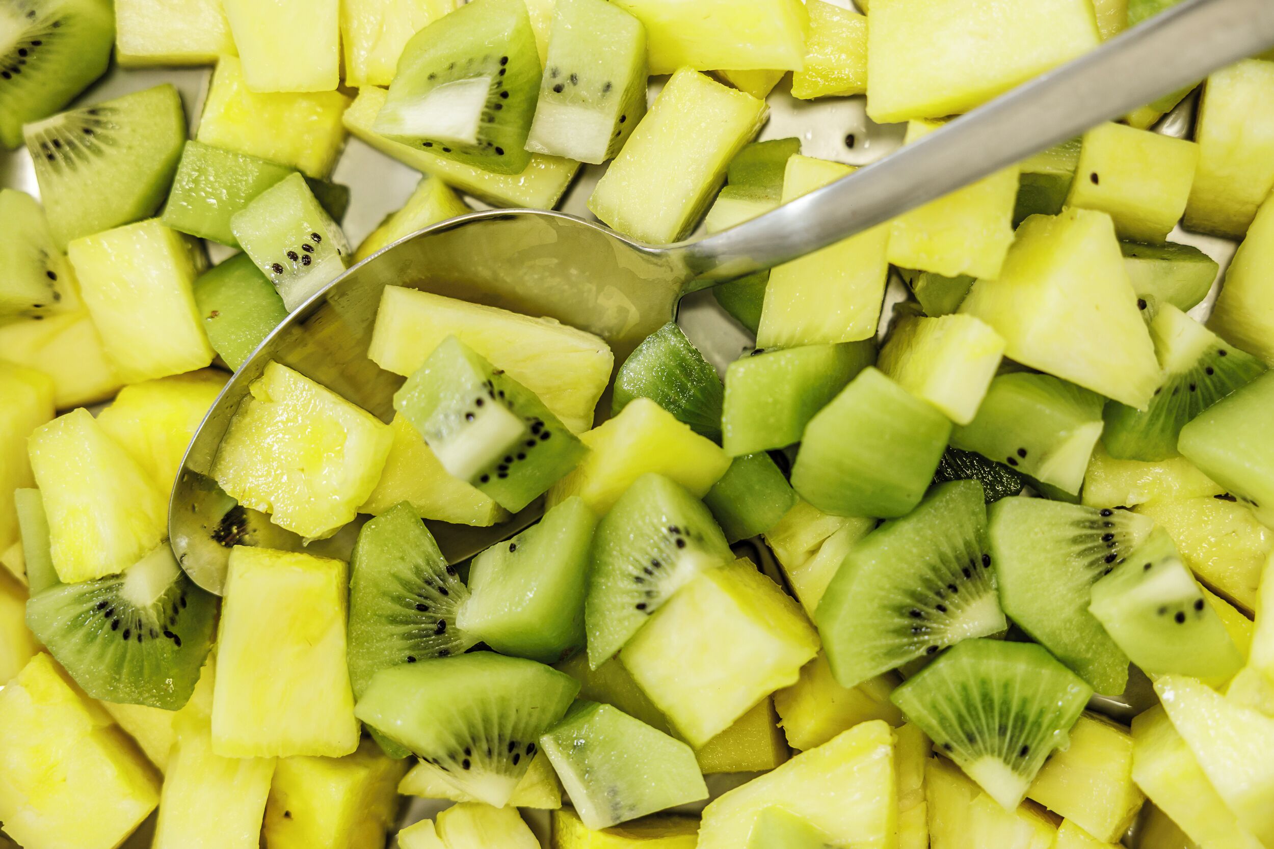 Eine Nahaufnahme von gewürfelten Kiwi- und Ananasstücken.