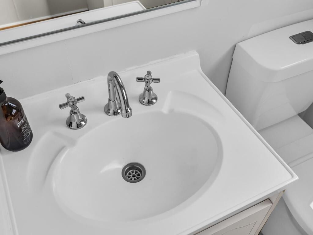 Un lavabo blanc amb dues aixetes i un vàter.