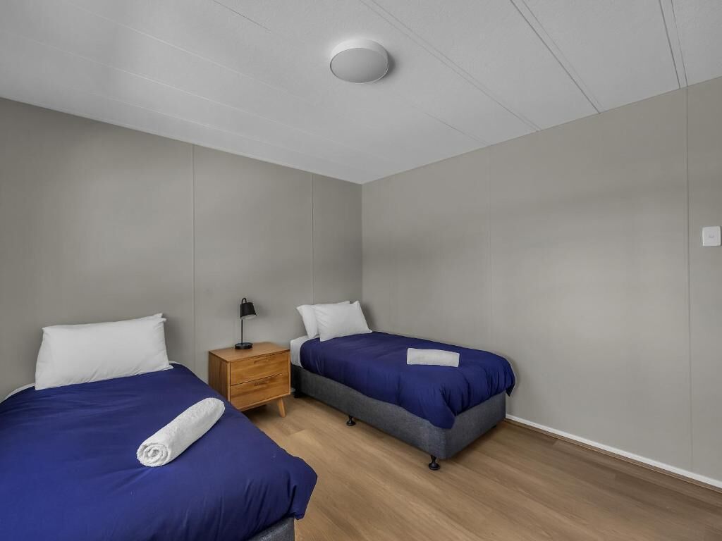 A twin room with two beds, a nightstand, and a ceiling light.