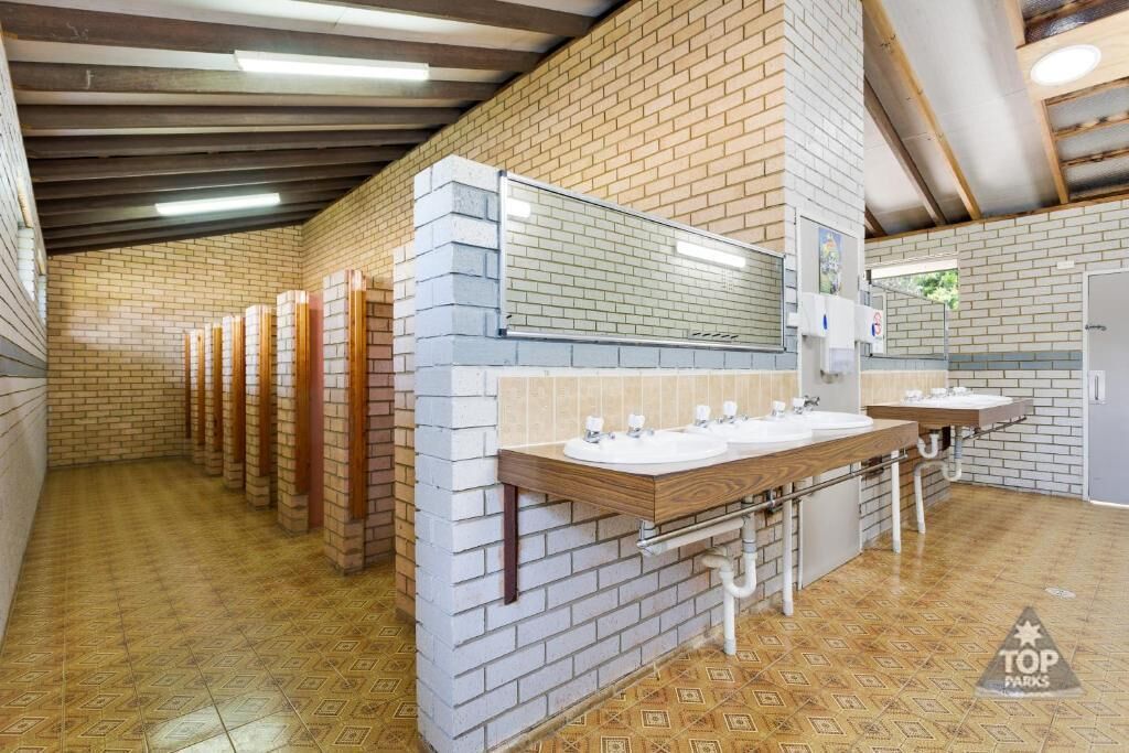 A public restroom with multiple sinks, a mirror, and a tiled floor.
