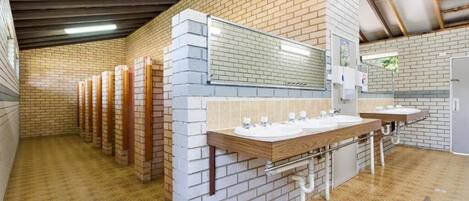 A public restroom with multiple sinks, a mirror, and a tiled floor.