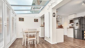 Una cocina moderna con tragaluz, muebles blancos y un refrigerador de acero inoxidable.