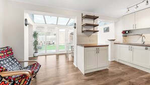 Una cocina moderna con armarios blancos, encimera de madera y un tragaluz.
