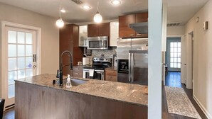 A modern kitchen with granite countertops, stainless steel appliances, and pendant lighting. - Walkable Dixieland District Gem with Yard (Lakeland)