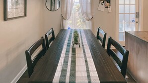 A dining area with a long table, chairs, a decorative runner, a mirror, and a door with a window view. - Walkable Dixieland District Gem with Yard (Lakeland)