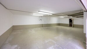 Et stort, tomt rum med lysstofrør, hvide vægge og beton gulv.