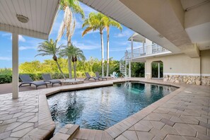 A swimming pool with lounge chairs, palm trees, and a stone wall. - 6B Waterfront Game Room Pool Hot Tub Dock (Palm Harbor)