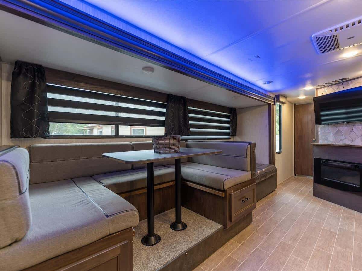 A compact kitchen with a built-in oven and a dining area with a table and bench seating.