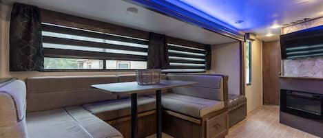 A compact kitchen with a built-in oven and a dining area with a table and bench seating.