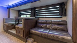 A compact RV interior with a leather couch, a small table, and a bench. - RV in Tampa Great Location Cost pet Friendly (Tampa)