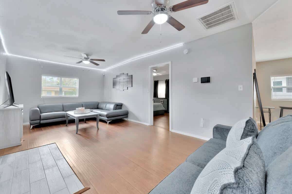 Un salon moderne avec un canapé gris, une table basse et un ventilateur de plafond.