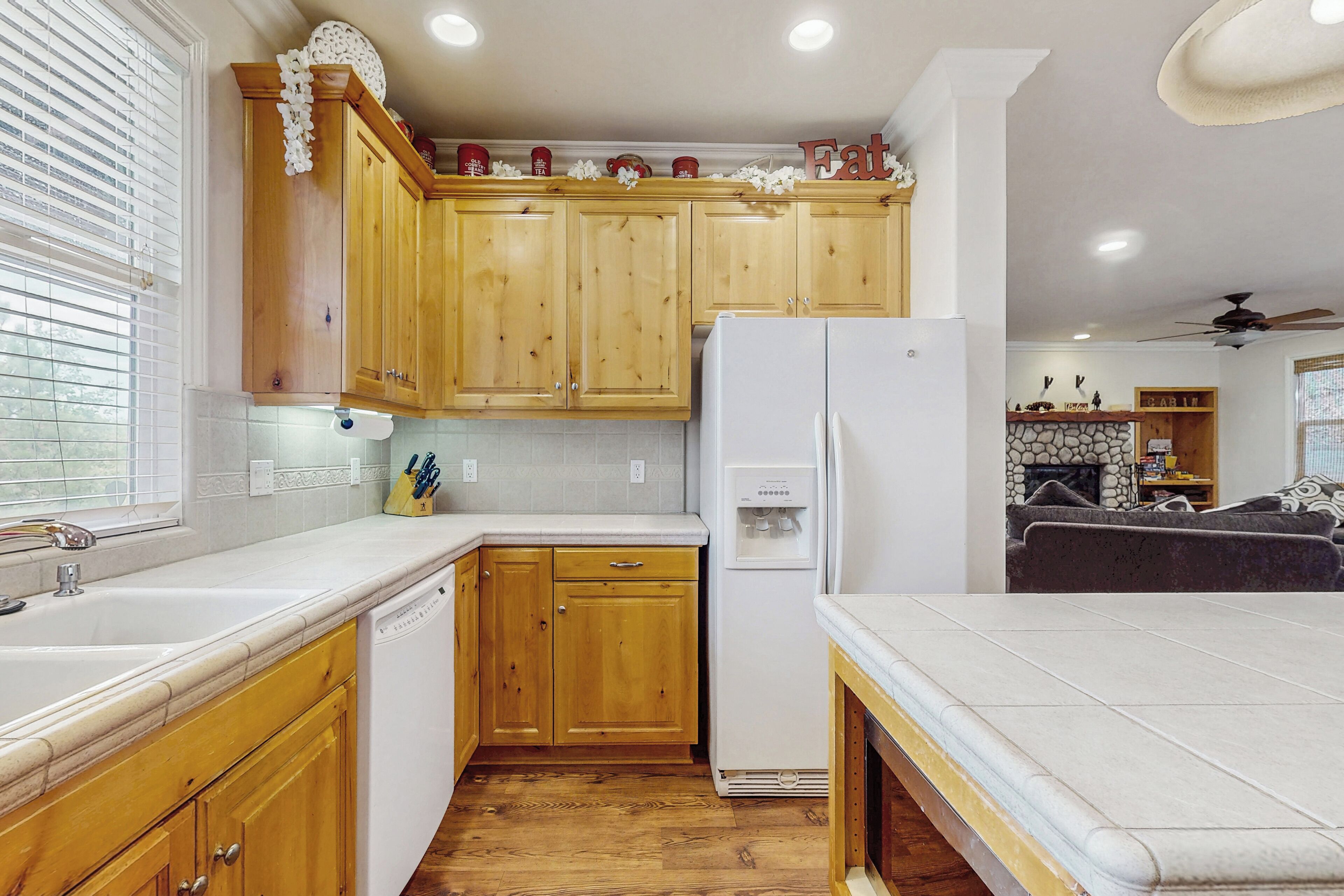 A kitchen with wooden cabinets, a refrigerator, and a countertop.