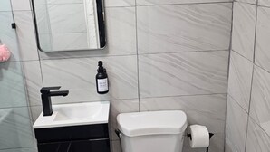 A modern bathroom with a white toilet, a black sink, and a mirror above the sink. - Ponce Pueblo Central Apt (Ponce)