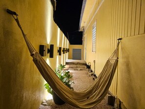 A hammock in a narrow corridor with yellow walls and a potted plant. - Ponce Pueblo Central Apt (Ponce)