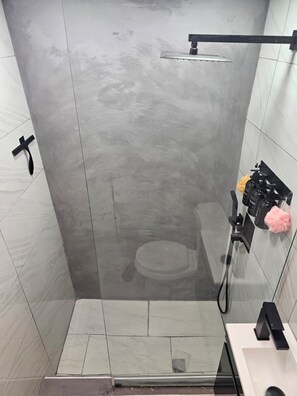 A modern shower with a glass door, a handheld showerhead, and a wall-mounted faucet. - Ponce Pueblo Central Apt (Ponce)