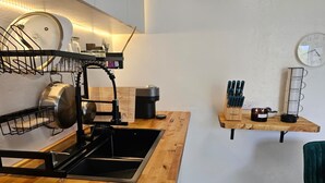 A modern kitchen with a built-in dishwasher, a coffee station, and a clock on the wall. - Ponce Pueblo Central Apt (Ponce)
