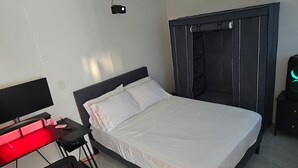 A bedroom with a bed, a desk with a computer, and a wardrobe. - Ponce Pueblo Central Apt (Ponce)