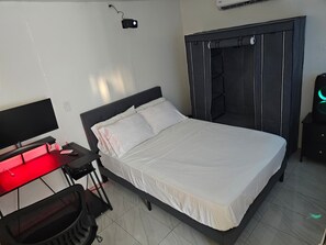 A bedroom with a bed, a desk with a computer, and a wardrobe. - Ponce Pueblo Central Apt (Ponce)