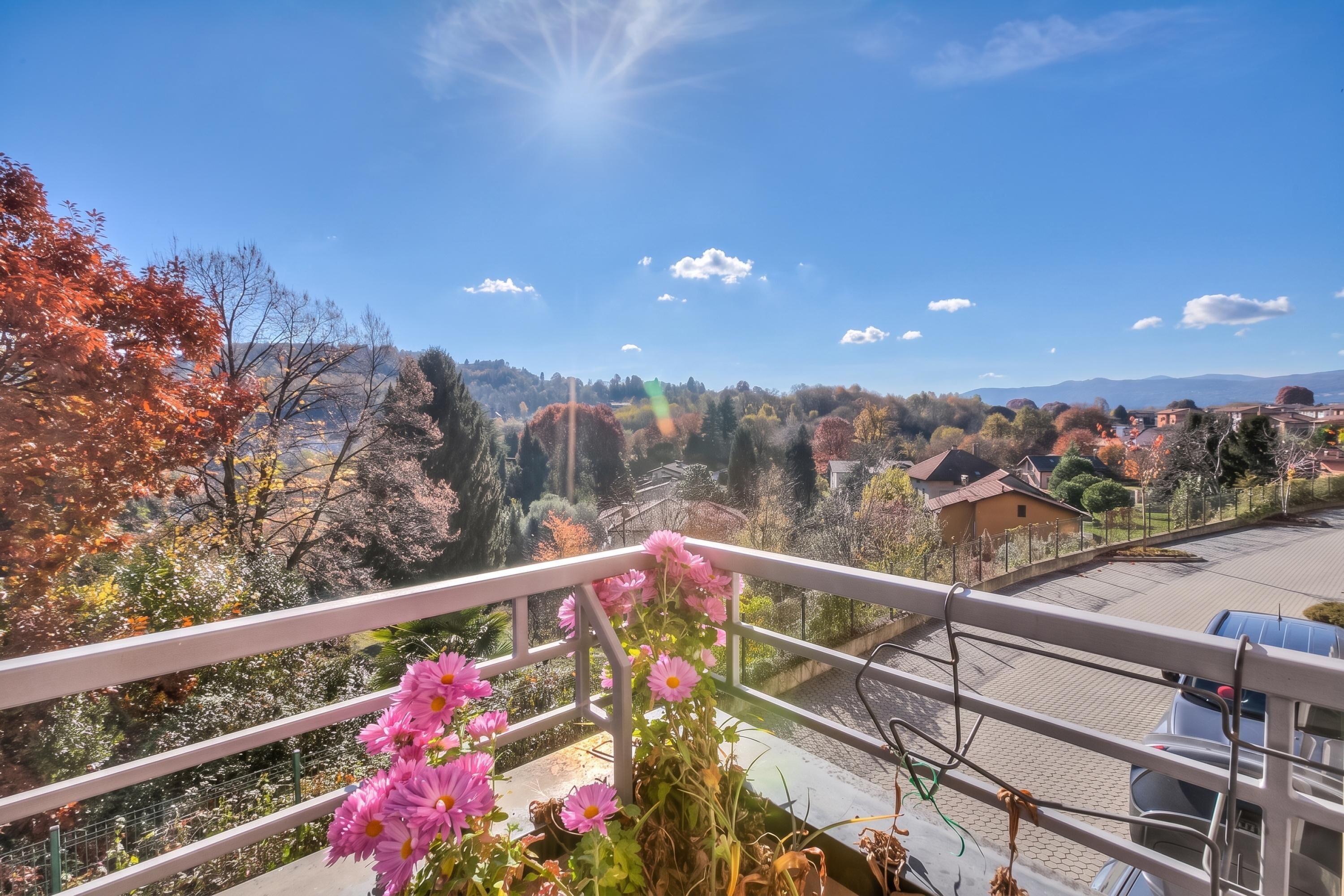 Ein Balkon mit Blick auf ein Wohngebiet, darunter Häuser und Bäume.